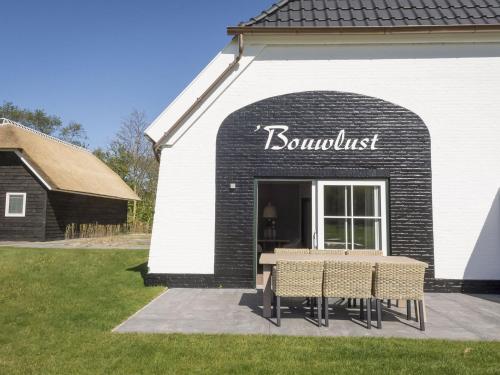デ・カクスドルプにあるCozy Farmhouse in Frisian Islandの建物の前にテーブルと椅子