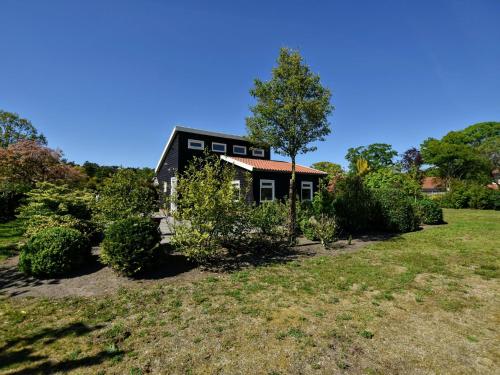 una casa negra con un árbol en un patio en Holiday home with wifi, en Eerbeek
