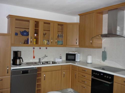 a kitchen with wooden cabinets and a sink at Ferienwohung Hanl - schöne FeWo mit 2 Schlafzimmern mit TV, Garten und großem Badezimmer in Wanderup