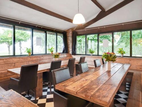 een grote eetkamer met houten tafels en stoelen bij Spacious farmhouse in Limburg near forest in Sint Antoniusbank