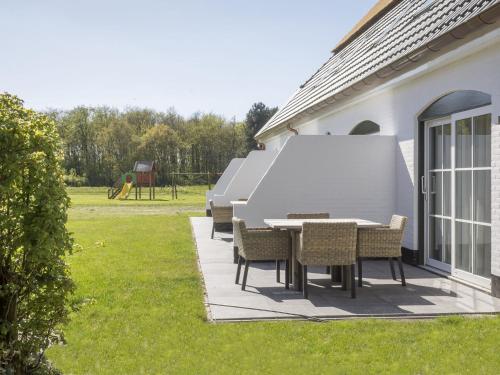 een patio met een tafel en stoelen in een tuin bij Apartment in tasteful farmhouse in De Cocksdorp on the Wadden island of Texel in De Cocksdorp