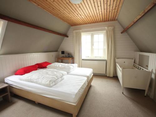 Schlafzimmer mit einem Bett mit weißer Bettwäsche und roten Kissen in der Unterkunft Nicely decorated villa with garden, near the sea in Hippolytushoef