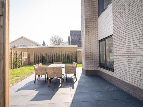 een patio met een tafel en stoelen aan de zijkant van een gebouw bij Modern Holiday Home in De Cocksdorp in De Cocksdorp