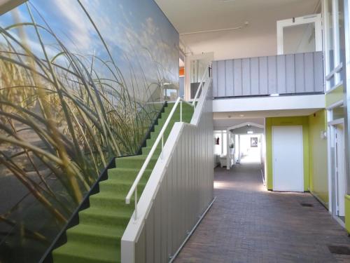 a hallway of a building with stairs and grass at Apartment near the sea in Hollum in Hollum