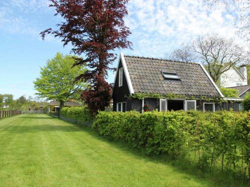 een zwart huis met een boom naast een tuin bij Holiday home for two people at a peaceful in Heiloo