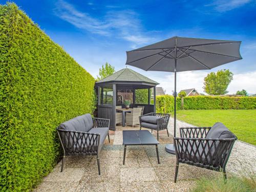 a patio with chairs and an umbrella and a gazebo at Premium Farmhouse in Zelhem with Sauna in Zelhem