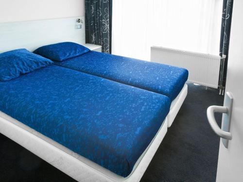 WestermientにあるStylish Holiday Home In Texel With Saunaの青い枕が付いたベッド1台が備わる客室です。
