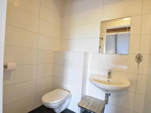 a white bathroom with a toilet and a sink at Apartment near Groote Keeten Beach in Callantsoog