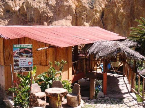 a small building with a red roof on a mountain at Paraiso Las Palmeras Lodge in Cabanaconde