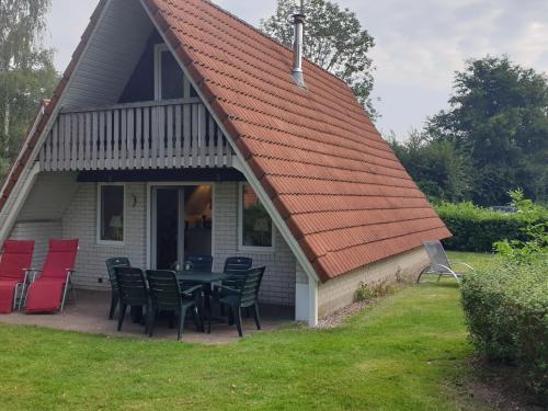 una casa con techo naranja con sillas y mesa en Nice holiday home in Gramsbergen on family park, en Gramsbergen