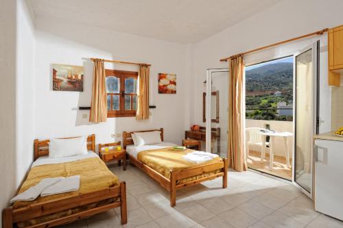 a bedroom with two beds and a balcony at Stelios Residence Apartments in Malia
