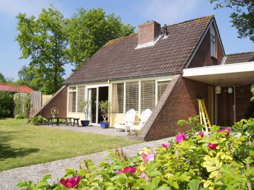 een stenen huis met een patio en bloemen bij Cosy holiday home in Lauwersoog in Lauwersoog