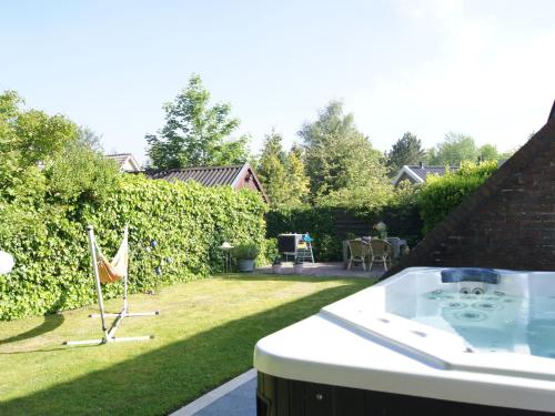 una bañera de hidromasaje en un patio con patio en Cosy holiday home in Lauwersoog, en Lauwersoog