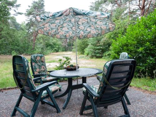 a patio table with two chairs and an umbrella at Holiday Home in Beerze Overijssel with Lush Garden in Beerze
