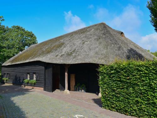 a hut with a thatched roof and a hedge at Unique holiday home with a hot tub in Alphen