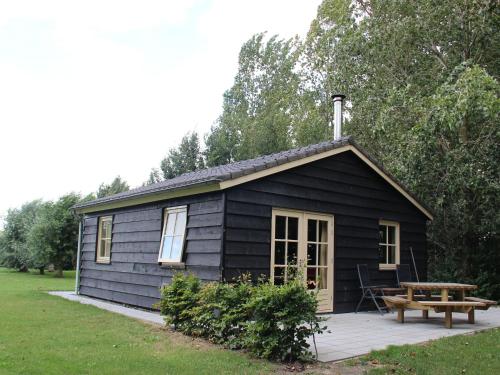 a black cabin with a picnic table and a bench at Cozy vacation home with terrace in Lage Zwaluwe