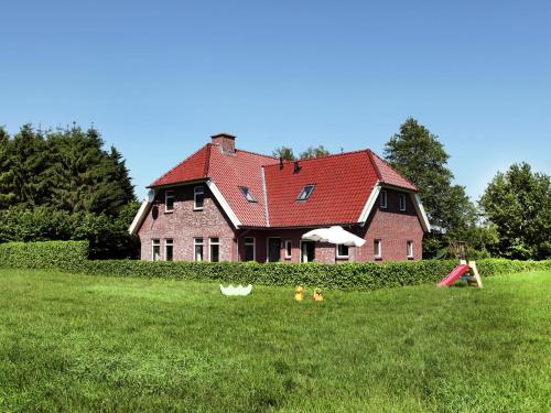 una casa con techo rojo en un campo en Spacious farmhouse in Achterhoek with play loft, en Neede