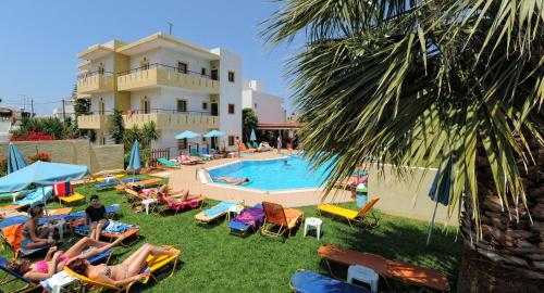 a group of people laying in lawn chairs by a pool at Stelios Residence Apartments in Malia