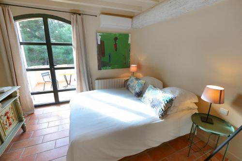 une chambre avec un lit blanc et une fenêtre dans l'établissement le mas de la bohéme, à Arles