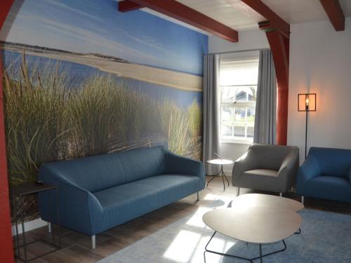a living room with two blue couches and a painting at Unique holiday home on Texel on the edge of Den Hoorn in Den Hoorn
