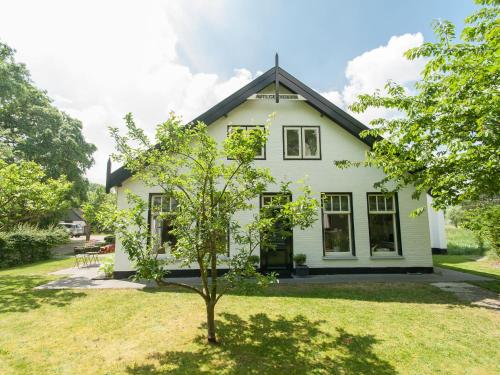 una casa blanca con un árbol en el patio en Attractive countryside holiday home in quiet, en Schoorl