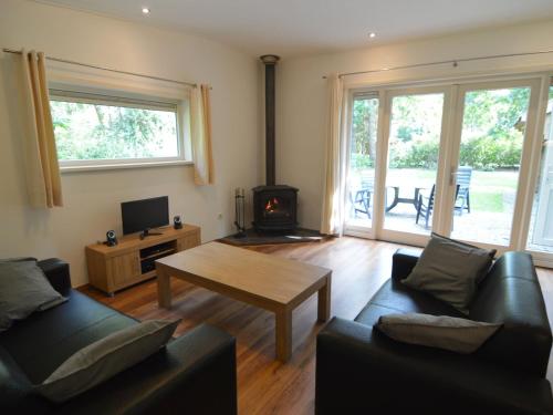 a living room with a couch and a table and a fireplace at Comfortable holiday home with a garden in Zelhem