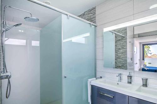 a bathroom with a shower and a sink and a mirror at Five Dreams Villas 2 dormitorios piscina privada in Corralejo