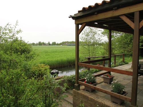 een paviljoen met een eend in een vijver naast een veld bij Holiday home in quiet surroundings in Sintjohannesga