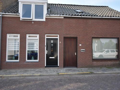 a red brick house with a black door and windows at Quiet holiday home in Nieuwvliet with a lounge area by the sea in Nieuwvliet