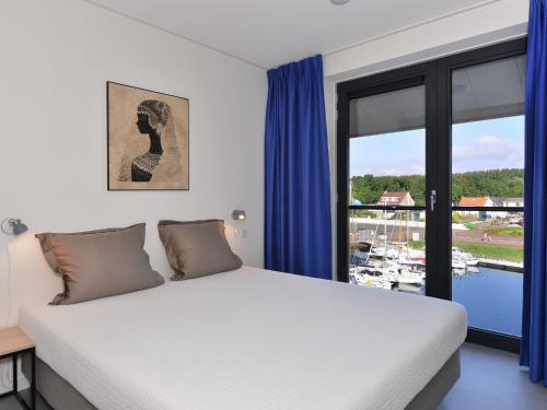 Un dormitorio con una cama grande con cortinas azules. en Waterfront Apartment with Terrace, en Kamperland