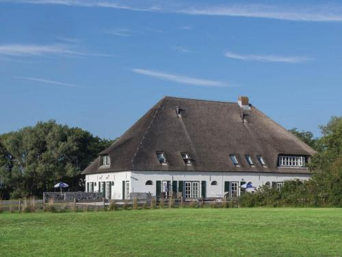 un grand bâtiment blanc avec un toit de chaume dans l'établissement Apartment in farmhouse on the island of Texel, à De Cocksdorp