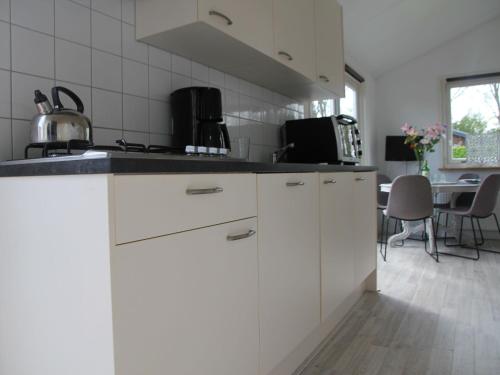 une cuisine avec des placards blancs et un comptoir dans l'établissement Comfortable bungalow near the beach, à Warmenhuizen