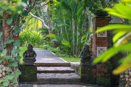 a stone path in a garden with two statues at Medori Putih Homestay in Uluwatu