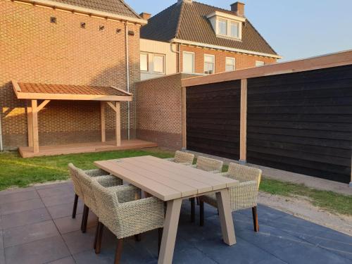 een houten tafel en stoelen op een patio bij Spacious bungalow in the cosy village in De Cocksdorp