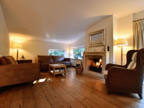 a living room with a couch and a fireplace at Attractive bungalow with sauna and hot tub in Voorthuizen