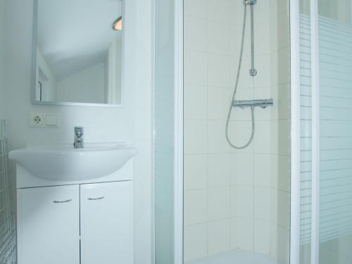 La salle de bains blanche est pourvue d'une douche et d'un lavabo. dans l'établissement Cozy chalet with a dishwasher, in a holiday park in a natural environment, à IJhorst