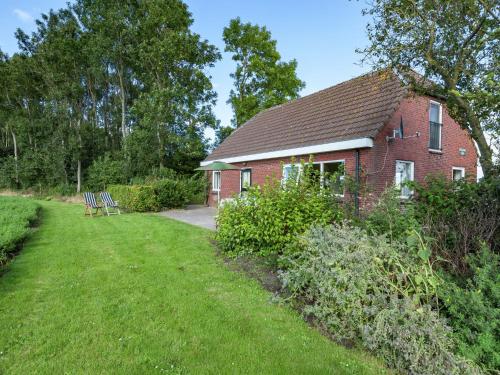 een klein rood bakstenen huis met een grasveld bij Peaceful vacation home in Finsterwolde with wide views in Finsterwolde