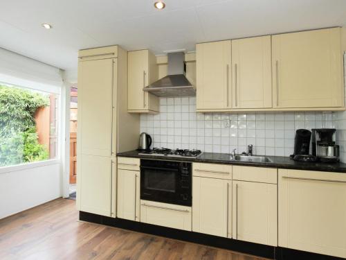 uma cozinha com armários brancos e um forno com placa de fogão em Cosy Holiday Home in Noordwijkerhout near Lake em Noordwijkerhout