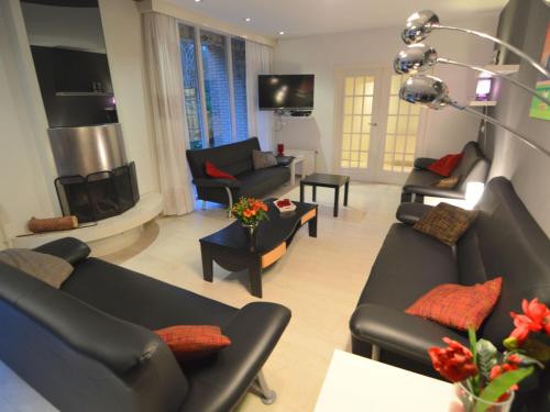 a living room with black couches and a fireplace at Family villa w Trampoline, Pool in Doornspijk