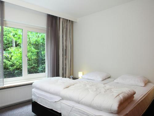 a white bedroom with two beds and a window at Family villa w Trampoline, Pool in Doornspijk