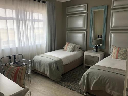 a bedroom with two beds and a mirror at Atlantic Villa Boutique Guesthouse in Swakopmund