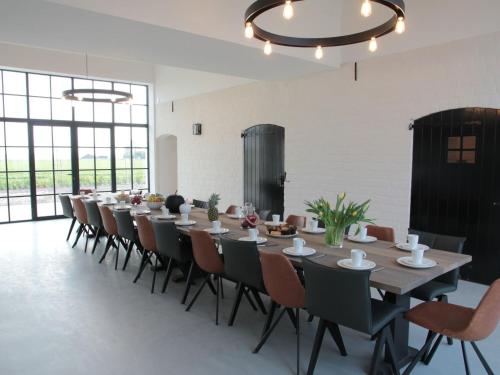 een lange eetkamer met een lange tafel en stoelen bij Countryside Villa in Zuidzande with Private Garden in Zuidzande