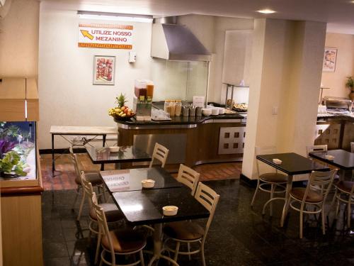 a restaurant with tables and chairs and a kitchen at Hotel Brasilia Curitiba in Curitiba