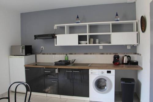 a kitchen with a sink and a washing machine at Le Gîte de La Tour Penchée in Soyons
