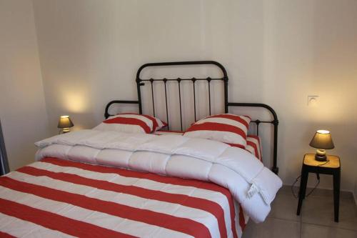 een bed met rode en witte gestreepte lakens en kussens bij Le Gîte de La Tour Penchée in Soyons