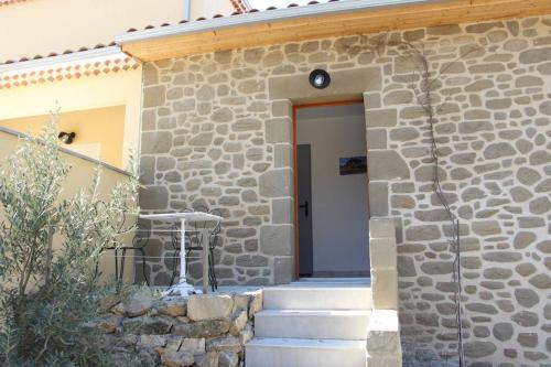 ein Steingebäude mit einer Tür und einer Treppe davor in der Unterkunft Le Gîte de La Tour Penchée in Soyons