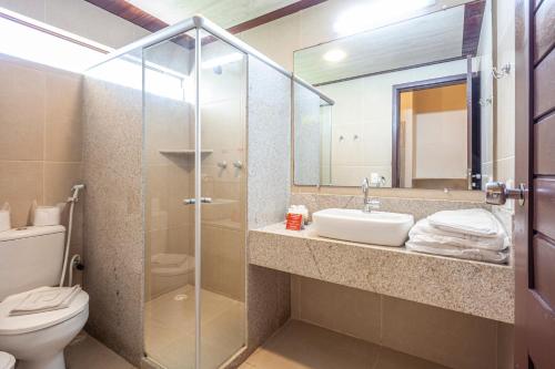 a bathroom with a sink and a toilet and a mirror at Ocaporã Hotel All Inclusive in Porto De Galinhas