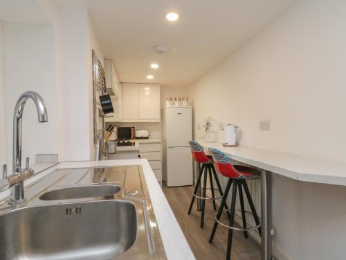 a kitchen with a sink and two bar stools at 47A Baxtergate in Whitby