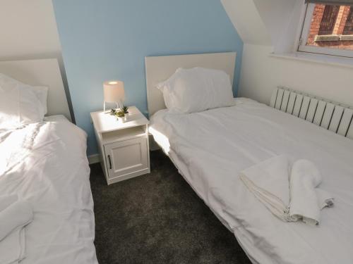 a bedroom with two beds and a night stand with a lamp at 47A Baxtergate in Whitby