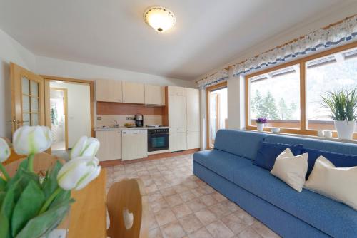 sala de estar con sofá azul y cocina en Haus-Schneider-Sepp, en Ettal